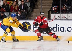 TORONTO, CANADA - DECEMBER 31: Sweden's Axel Holmstrom #25 keeps close watch on Switzerland's Kevin Fiala #10 during preliminary round action at the 2015 IIHF World Junior Championship. (Photo by Andre Ringuette/HHOF-IIHF Images)

